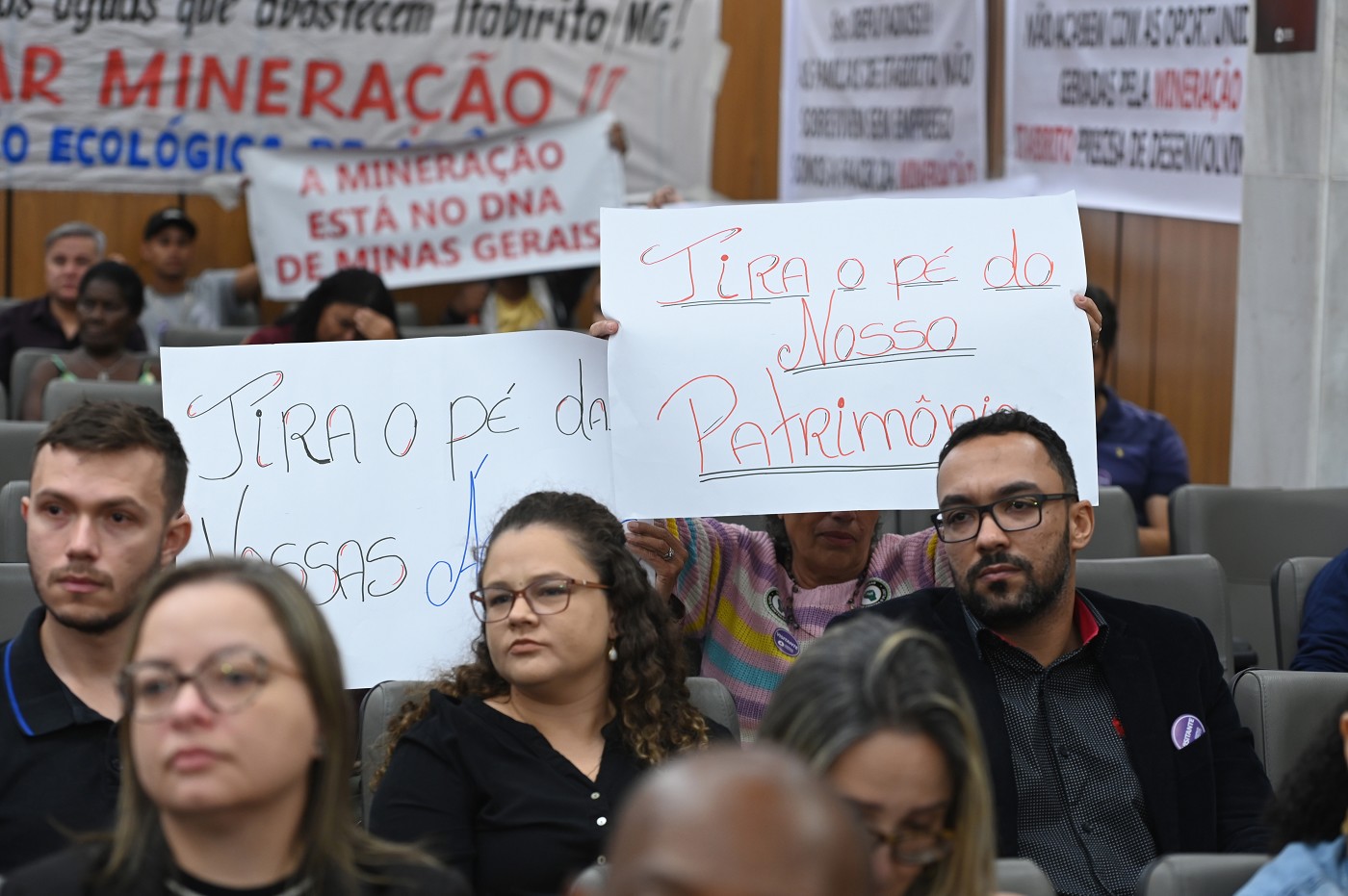 Participantes da reunião sobre Estação Ecológica de Arêdes levantam cartazes que dizem: "Tira o pé do nosso patrimônio" e "Tira o pé da nossas águas".